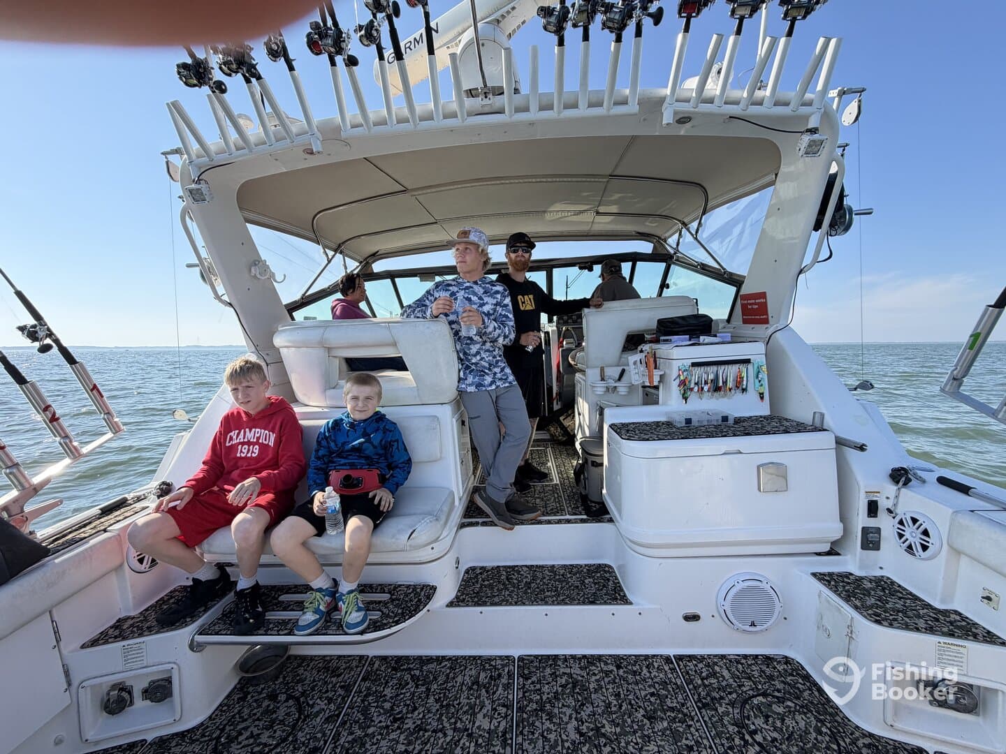A family enjoying their time on a fishing charter, seated in the boat's interior with fishing gear visible.