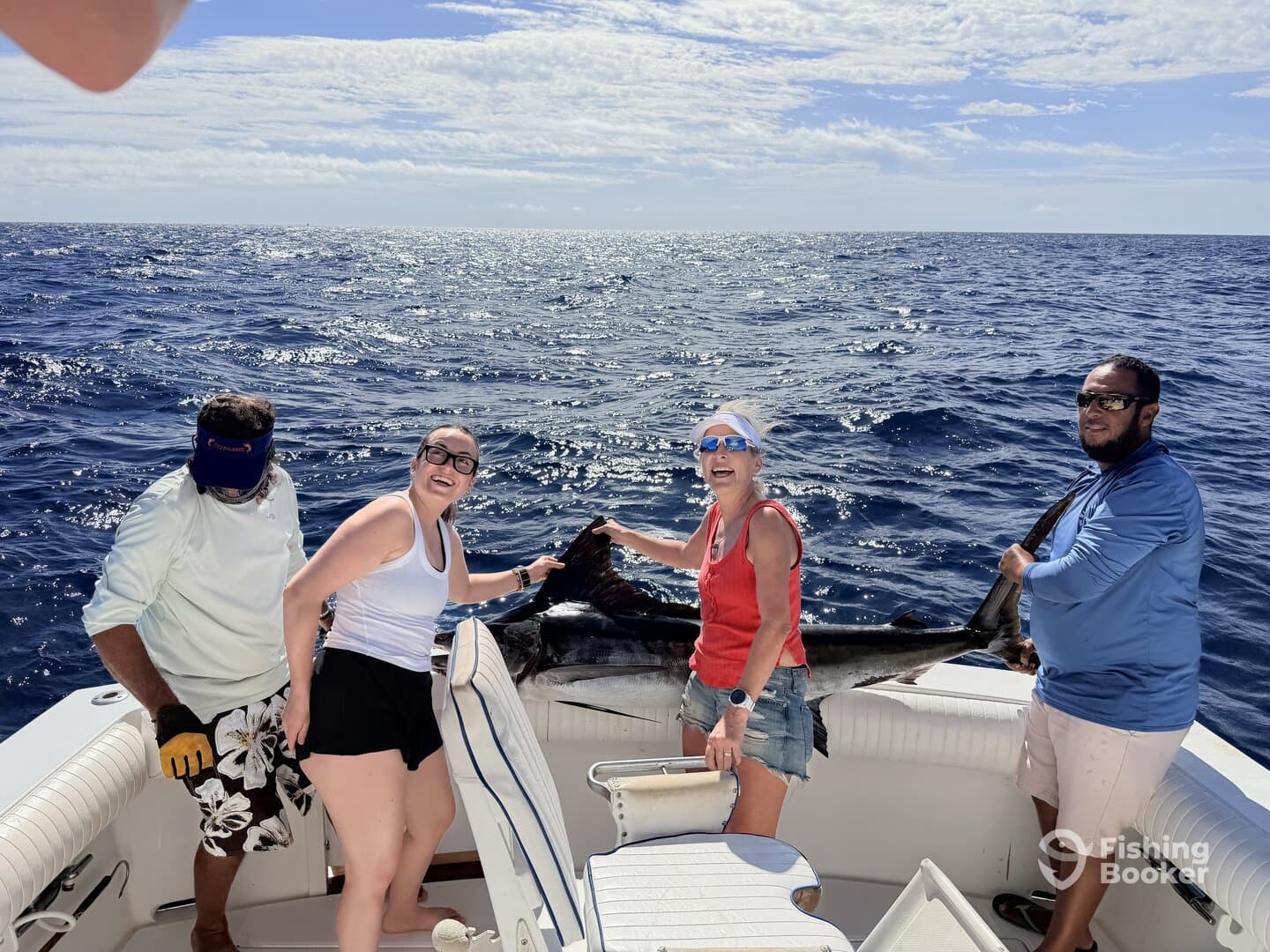 A group of anglers celebrating a successful catch of a large marlin while out on the open ocean.