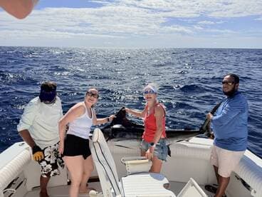 A group of anglers celebrating a successful catch of a large marlin while out on the open ocean.