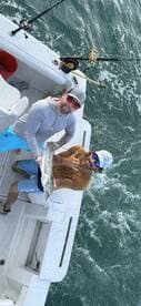 Two anglers proudly displaying a large Barracuda while fishing on a charter boat.