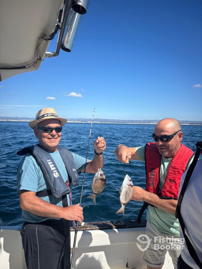 Two anglers proudly displaying their catches of Snapper while fishing on a sunny day.