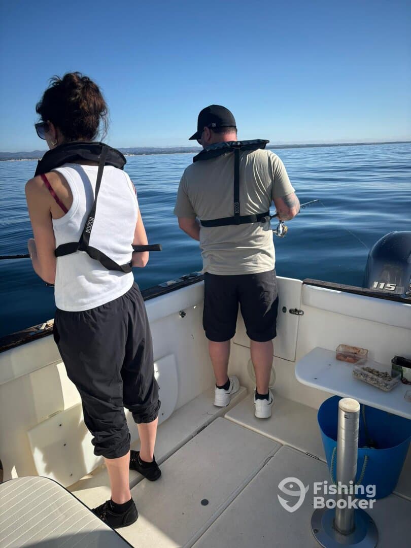 Two anglers actively fishing from a boat, enjoying a calm day on the water.