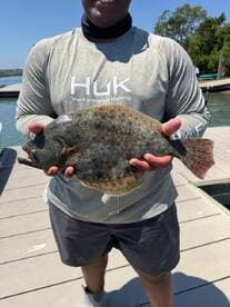 Angler proudly displaying a Flounder caught at the dock, showcasing a successful day of fishing.