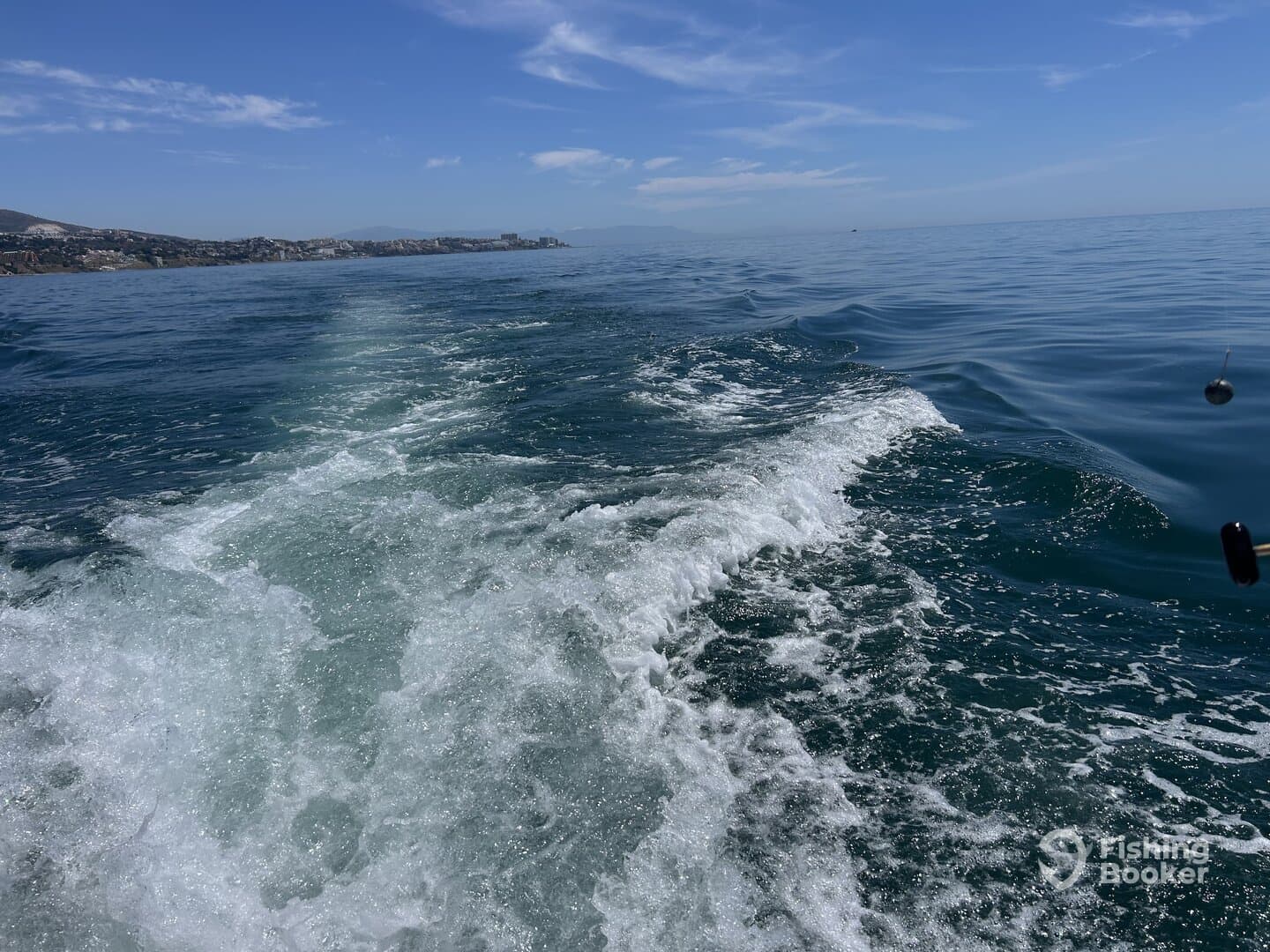 A scenic view of the ocean with boat wake, showcasing a calm fishing environment.