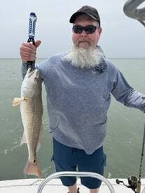 Angler proudly displaying a large Redfish while fishing on a boat in coastal waters.