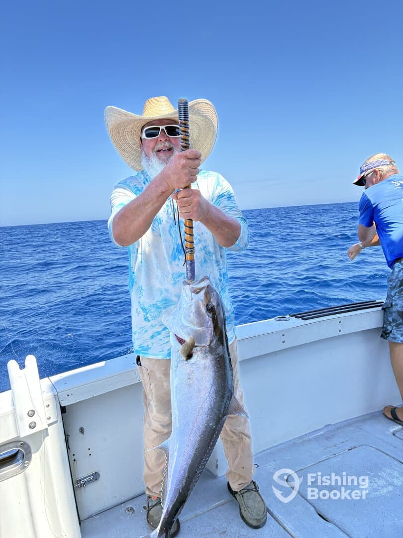 An angler proudly displaying a large fish while fishing offshore, showcasing a beautiful day on the water.