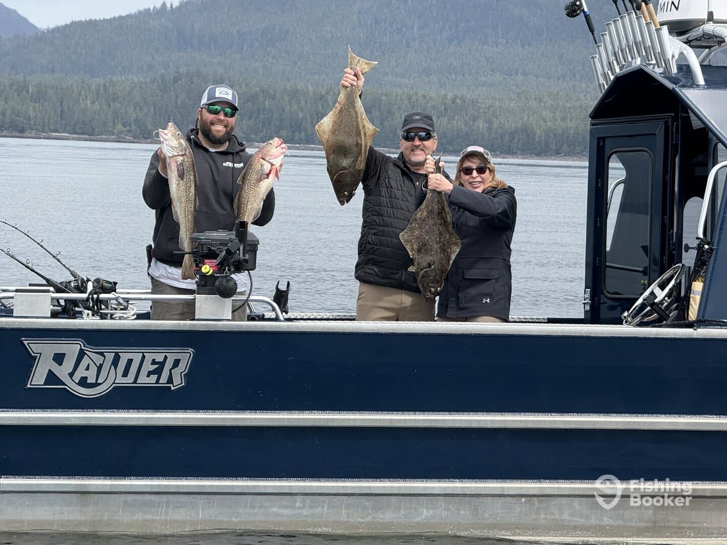 Three anglers proudly displaying their catch of Lingcod and Halibut aboard a Raider boat in a scenic fishing environment.