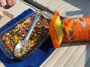 A colorful dish with various ingredients is displayed on a boat's seating area, showcasing a meal prepared during a fishing trip.