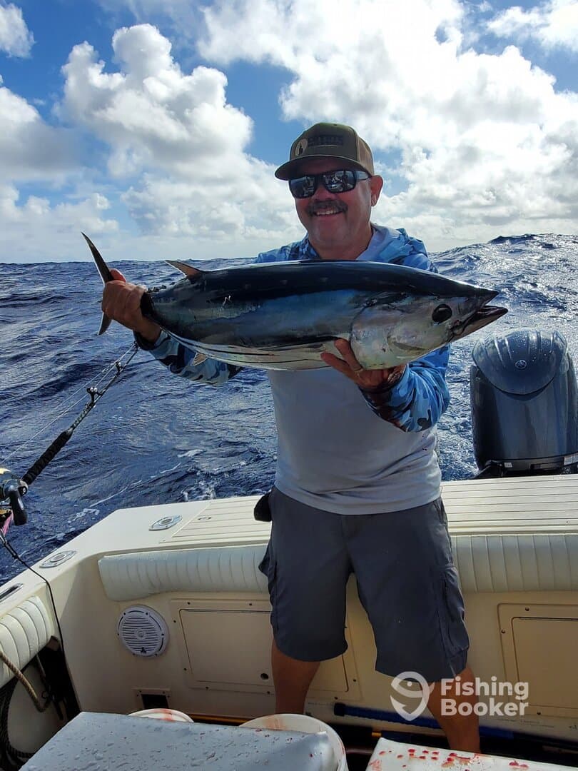 Angler proudly holding a large Tuna while fishing offshore, showcasing a successful day on the water.
