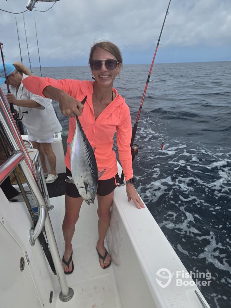 A proud angler holding a beautiful fish while fishing on a boat in open waters.