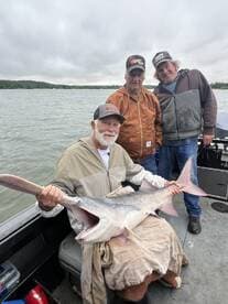 A group of anglers proudly displaying a large catfish while fishing on a lake, showcasing a successful day on the water.