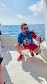 Angler showcasing a caught fish while fishing in open waters, enjoying a sunny day on the boat.