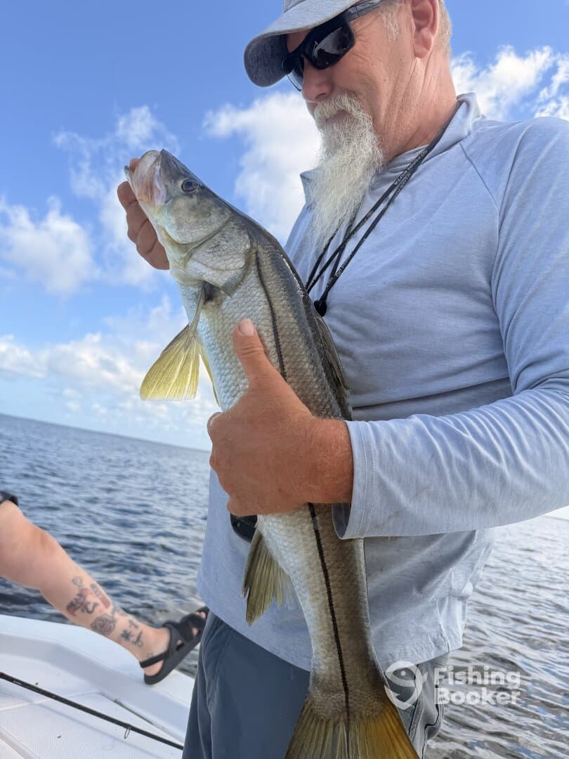 An angler proudly displaying a Snook while fishing on a sunny day.