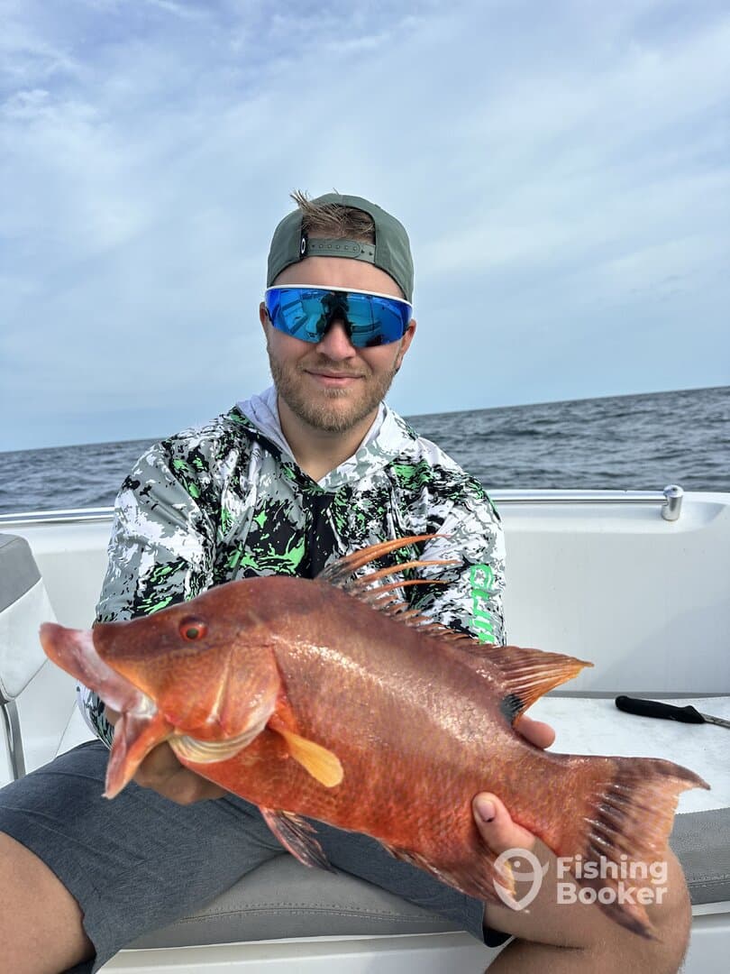 Angler proudly displaying a vibrant Red Snapper while fishing offshore, showcasing a successful day on the water.