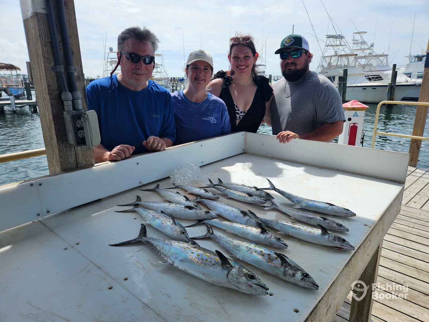 A group of anglers proudly displaying their catch of Spanish Mackerel on a cleaning table at the marina.