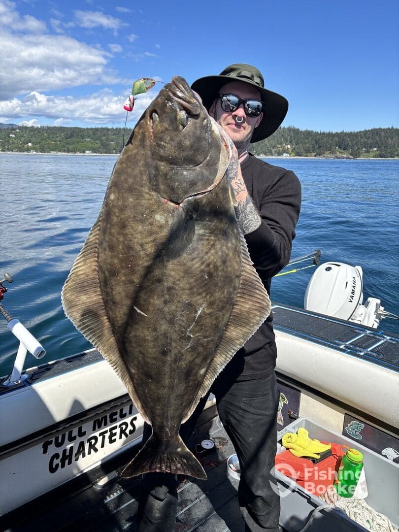 Angler proudly displaying a large Halibut caught during a charter fishing trip, with a scenic backdrop of the coastline.