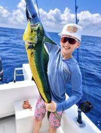 A young angler proudly displaying a vibrant Mahi Mahi while fishing offshore, showcasing the excitement of a successful catch.