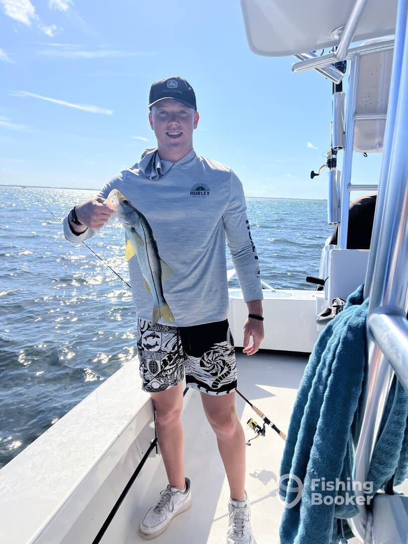 Angler proudly displaying a Snook while fishing on a sunny day in open waters.