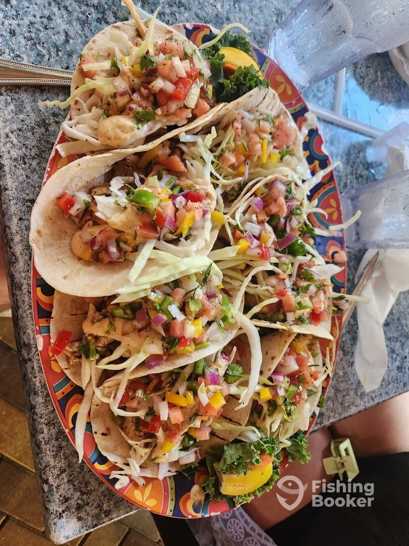 A vibrant plate of fish tacos garnished with fresh vegetables, served in a casual dining setting.