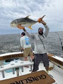 Angler proudly displaying a large Jack Crevalle while fishing aboard the 'Gunslinger' in open waters.