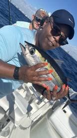 A proud angler holding a vibrant Yellowfin Tuna while fishing on a sunny day.