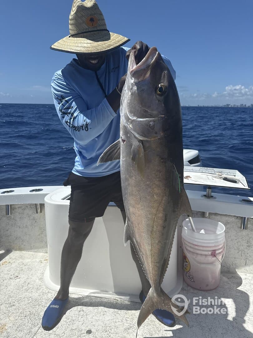 Angler proudly displaying a large Amberjack while fishing in open waters, showcasing a successful day on the boat.