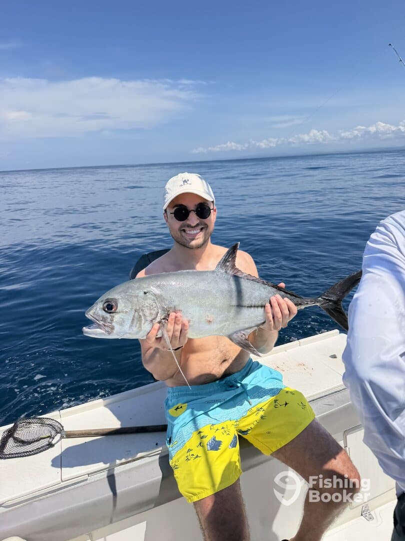 Angler proudly displaying a large fish while enjoying a sunny day on the water, showcasing a vibrant fishing environment.