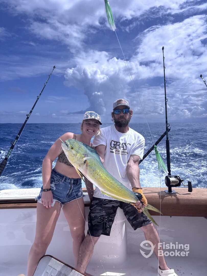 Two anglers proudly displaying a large Mahi Mahi while fishing offshore, showcasing a beautiful day on the water.