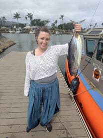 A proud angler holding a large Tuna at the dock, showcasing a successful fishing trip.