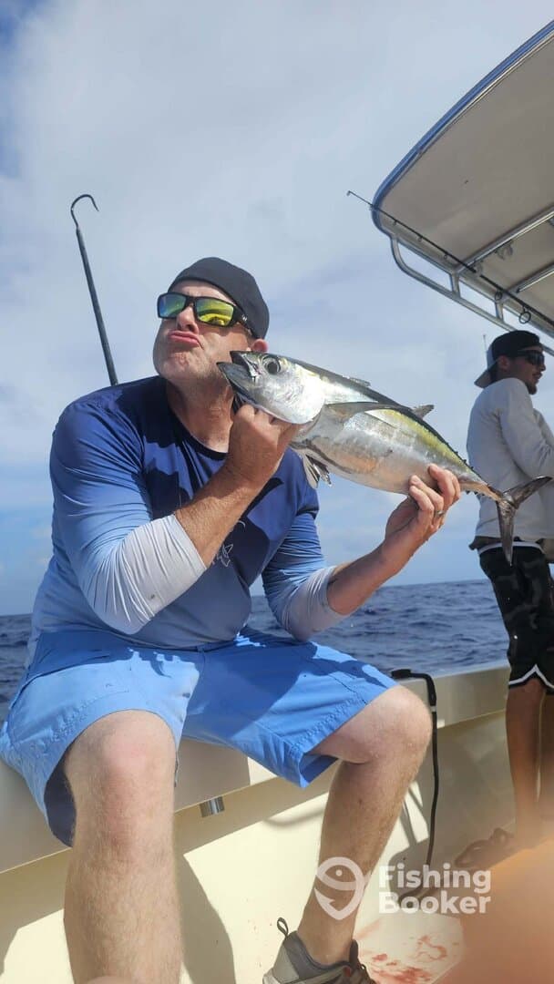 Angler proudly displaying a large fish while fishing offshore, showcasing a vibrant ocean backdrop.