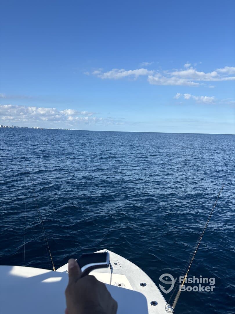 A view from the boat showing the open ocean and fishing gear, with a hand visible on the boat's edge.
