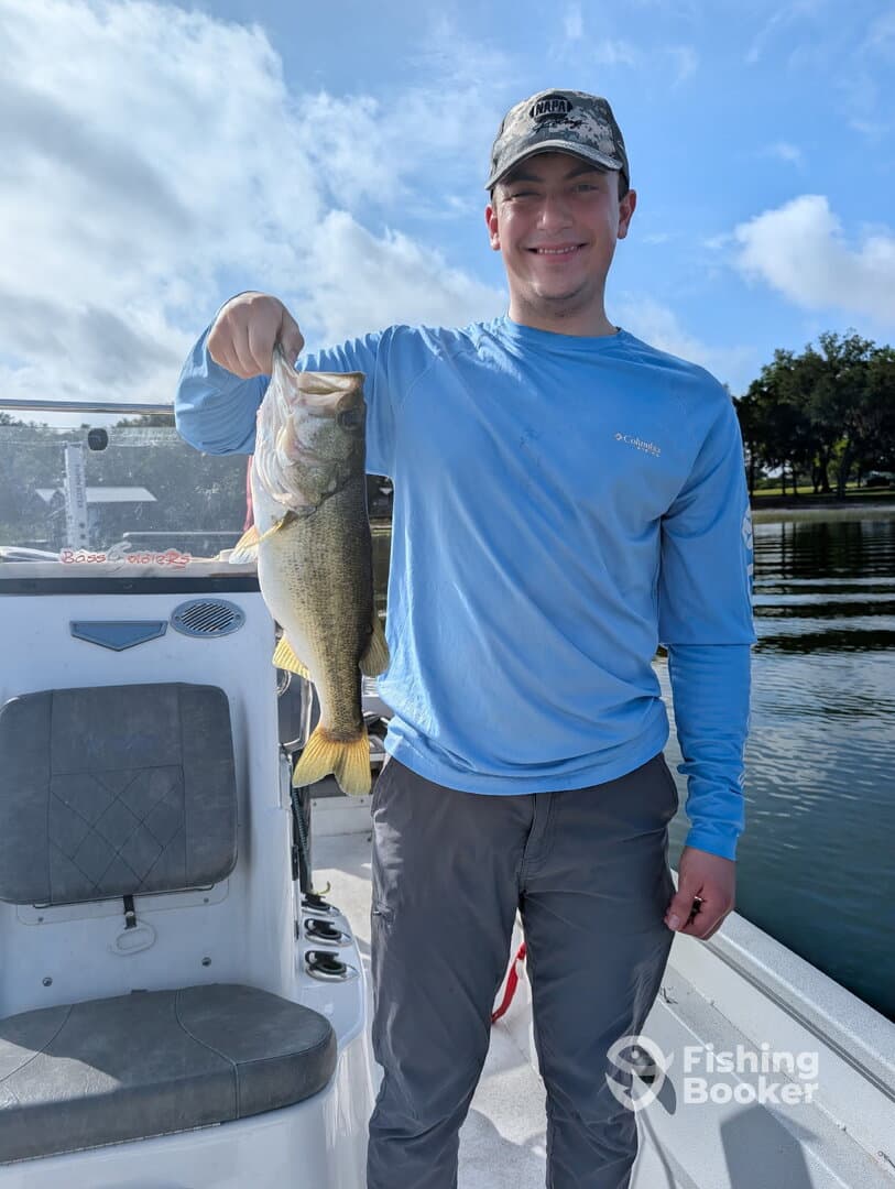 A young angler proudly displaying a large Largemouth Bass while on a fishing trip, showcasing the excitement of freshwater fishing.