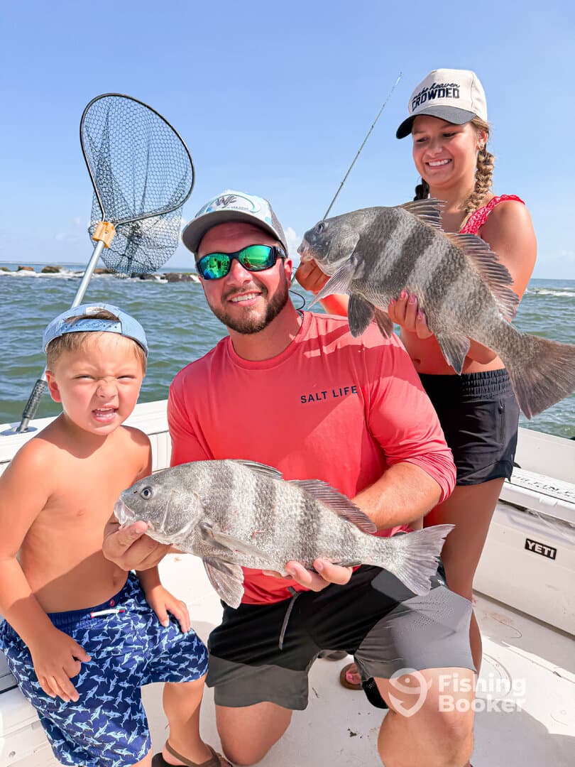 A family enjoying a successful fishing trip, proudly displaying their catch of Black Drum while on a boat.