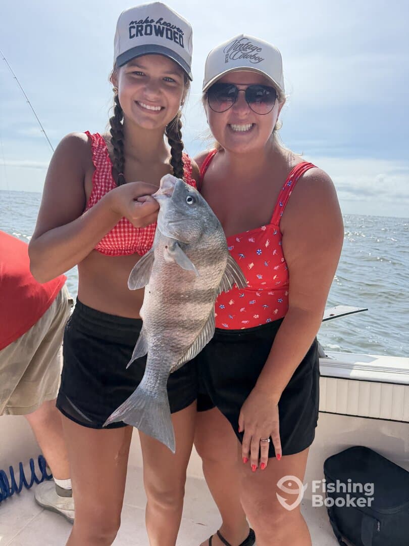 Two anglers proudly displaying a large Black Drum caught during a fun day of fishing on the water.