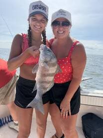 Two anglers proudly displaying a large Black Drum caught during a fun day of fishing on the water.