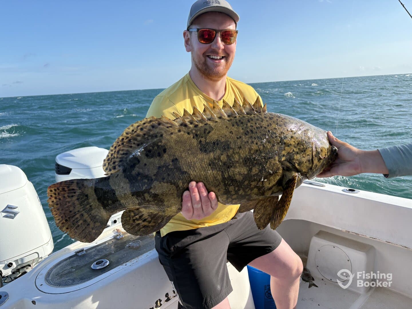 Angler proudly displaying a large Goliath Grouper while fishing offshore, showcasing the excitement of a successful catch.