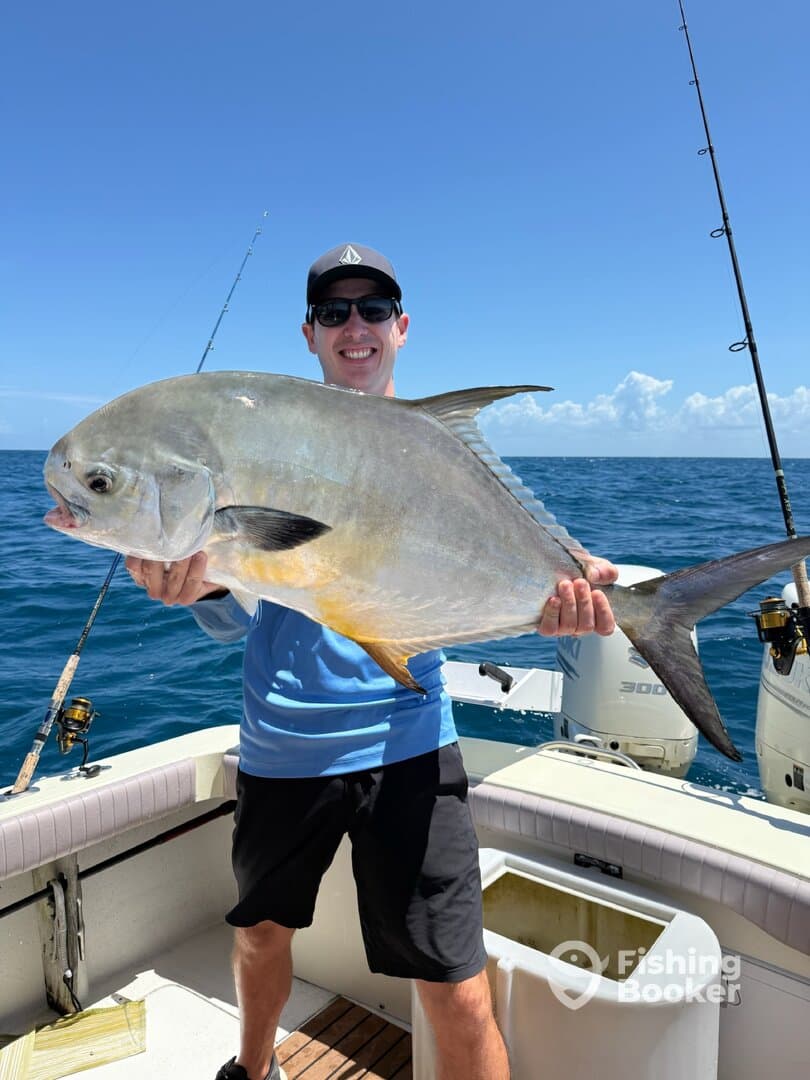 Angler proudly displaying a large Permit caught while fishing offshore, showcasing a beautiful day on the water.
