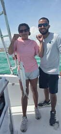 Two anglers proudly displaying a caught fish while enjoying a sunny day on the water.