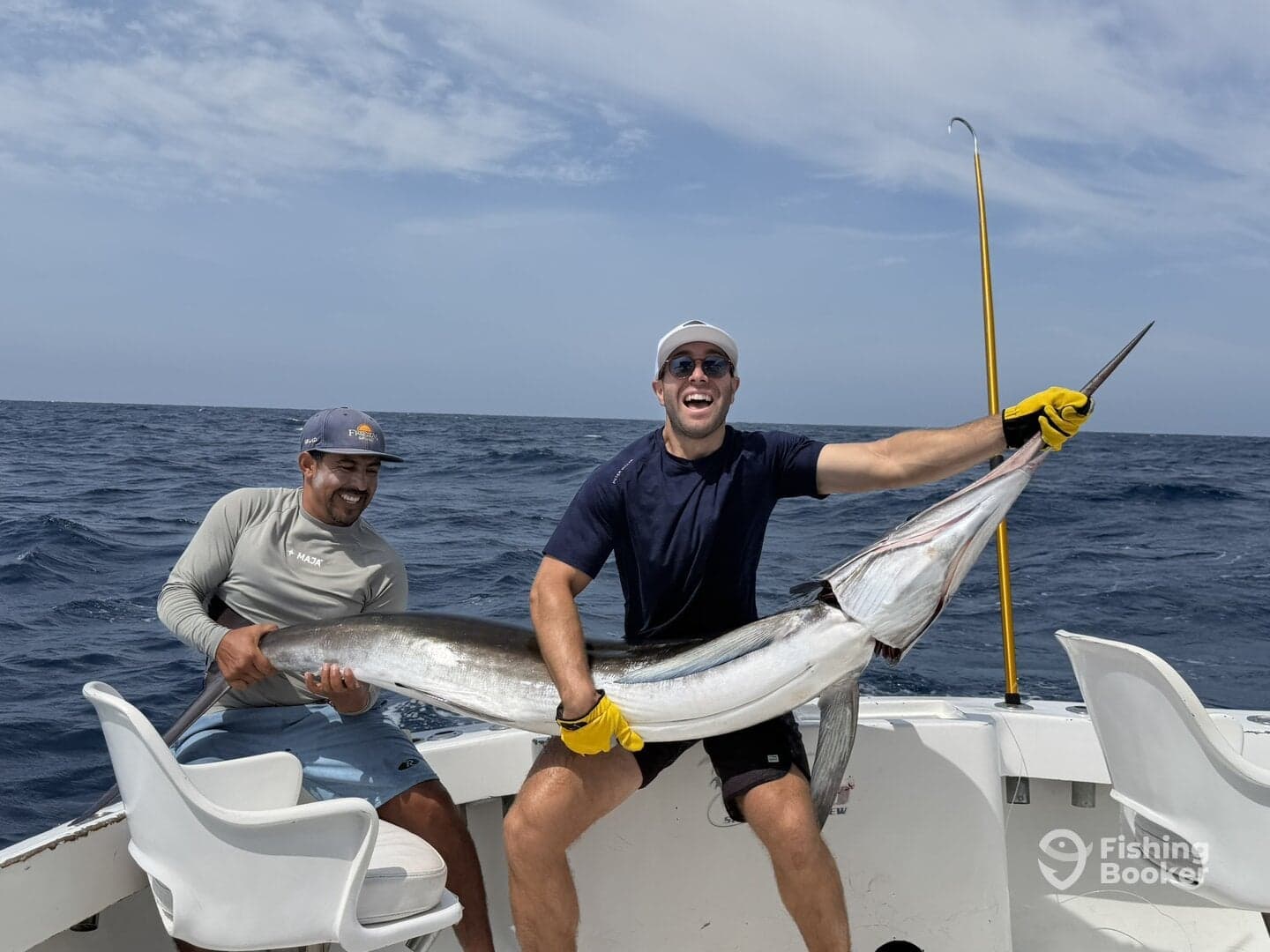 Two anglers celebrating a successful catch of a large fish while out on the open ocean.