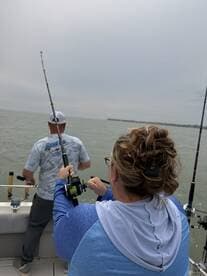 Angler reeling in a catch while fishing on a boat, showcasing the excitement of the fishing experience.
