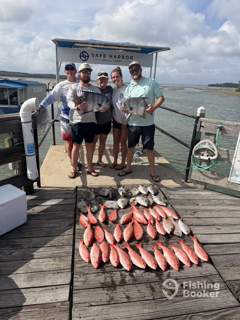 A group of anglers proudly displaying their catch of red snapper and other fish at Safe Harbor in Skull Creek after a successful fishing trip.