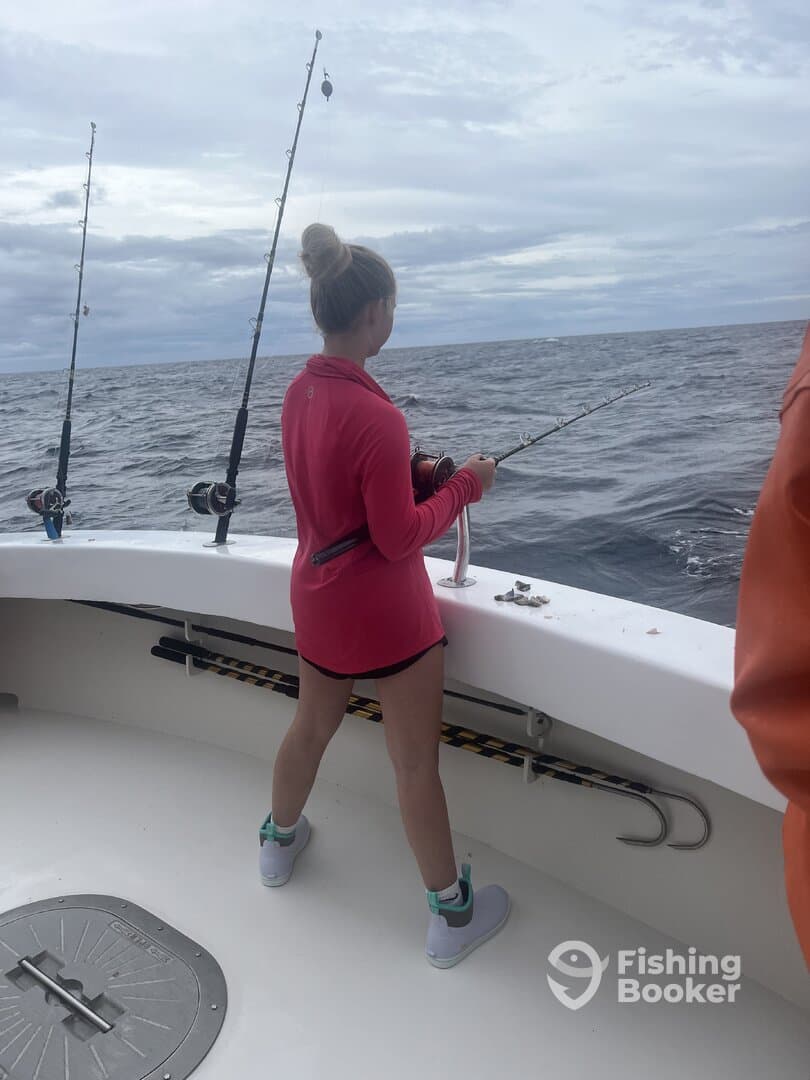 A young angler casting a line while fishing on a boat, showcasing the excitement of deep-sea fishing.