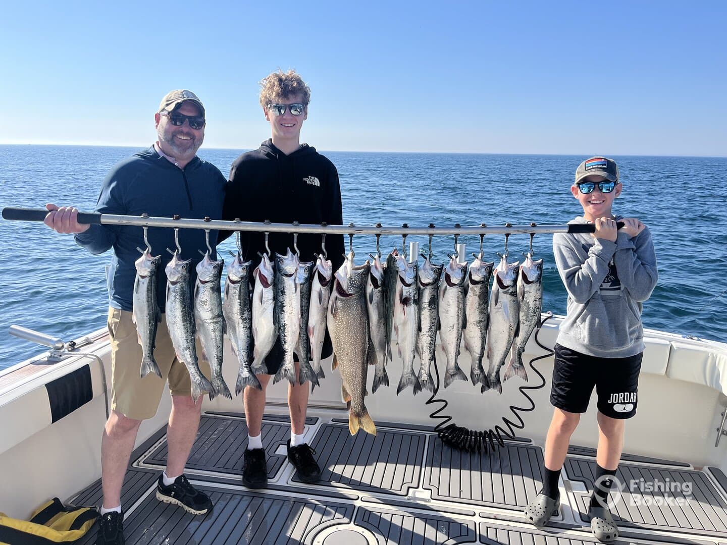 A family proudly displaying their catch of salmon on a fishing charter, showcasing a successful day on the water.