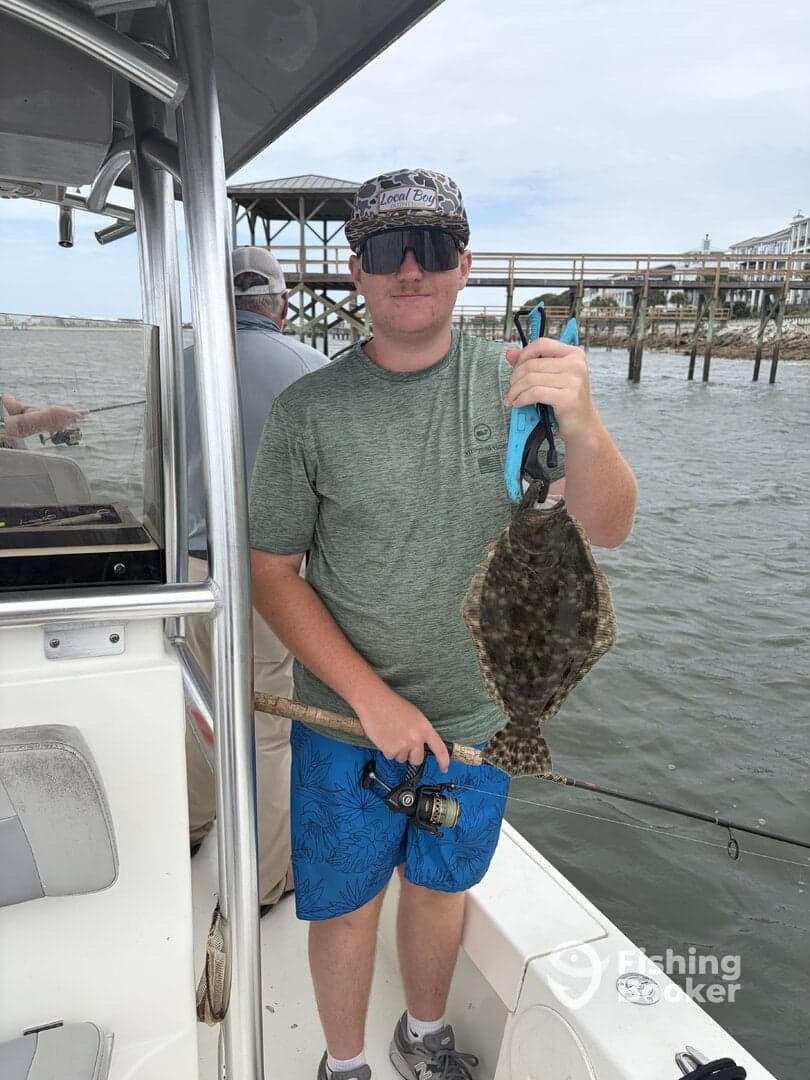 Young angler proudly holding a Flounder while fishing from a boat, showcasing a successful catch during a coastal fishing trip.