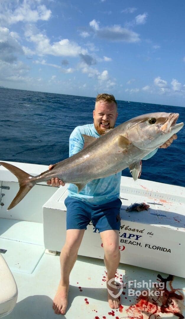 Angler proudly displaying a large Amberjack caught during a deep-sea fishing trip off the coast of Florida.