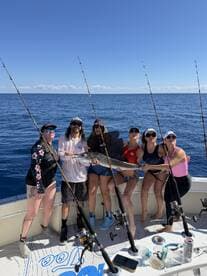 A group of anglers proudly displaying a large fish on a fishing charter in open waters, showcasing a fun day out on the boat.