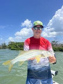 Angler proudly displaying a Snook caught while fishing in a scenic coastal environment.