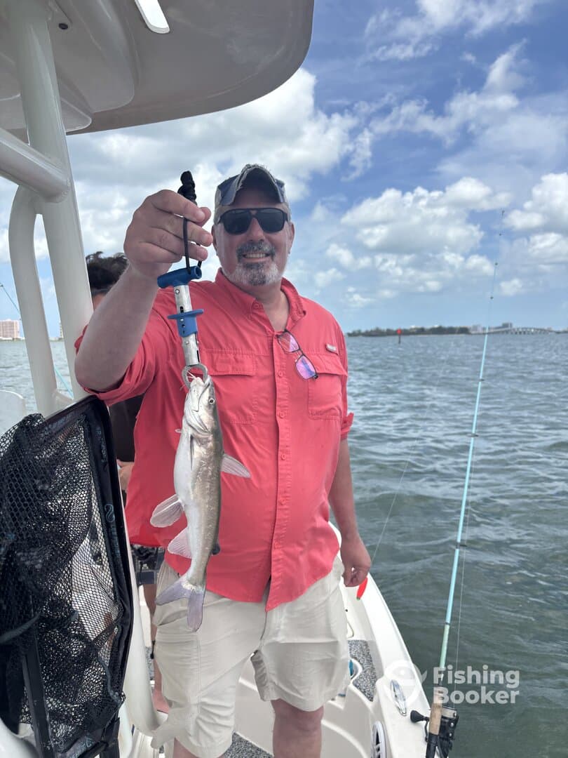 A proud angler holding a freshly caught fish while enjoying a day on the water, showcasing a successful fishing trip.
