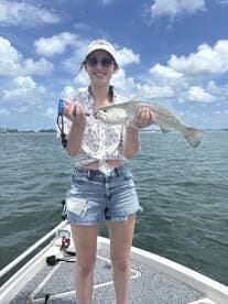 A young angler proudly displaying a Speckled Trout while fishing on a sunny day.