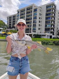 A young angler proudly displaying a Snook while fishing near a waterfront property.
